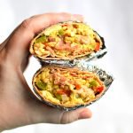Holding a split in half breakfast burrito.